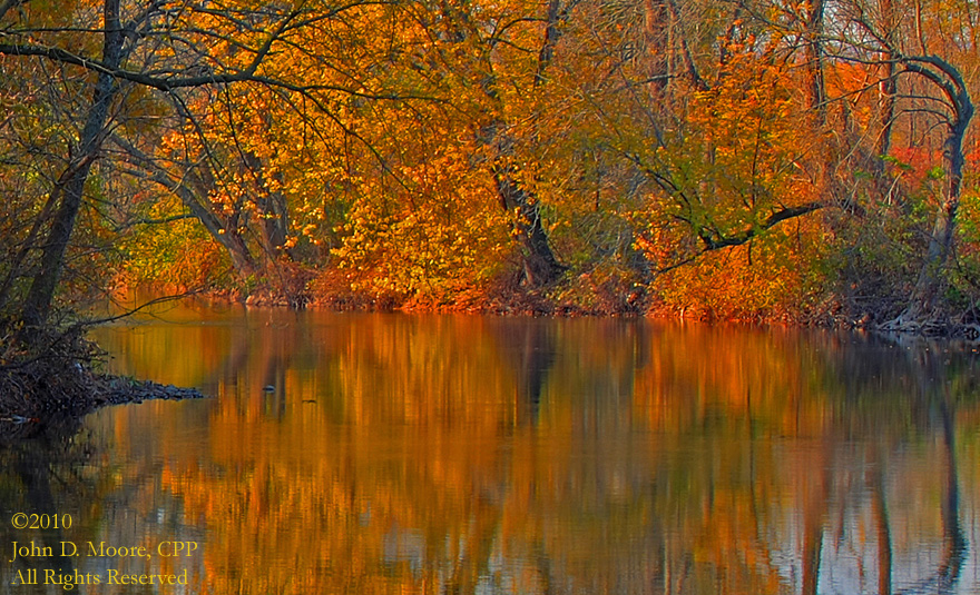 Before the Pennsylvania sun sets, the autumn colors are reflected in the river.